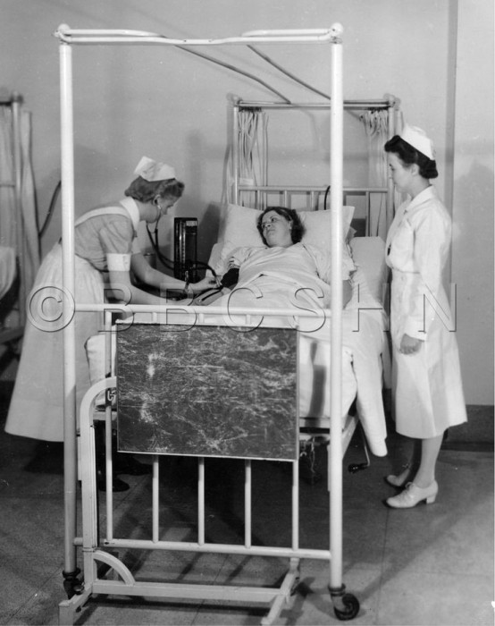 A student nurse at a bedside taking a patient's blood pressure while Instructor Sarah P. White looks on, Hospital of the University of Pennsylvania, 1942. Image courtesy of the Barbara Bates Center for the Study of the History of Nursing.